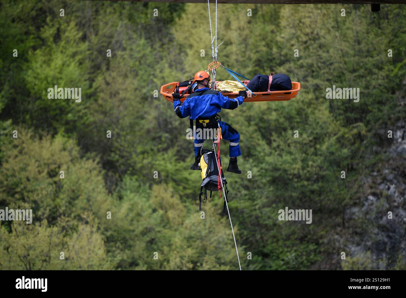 Emergency rescue operation as rescuer descends bridge carrying ...