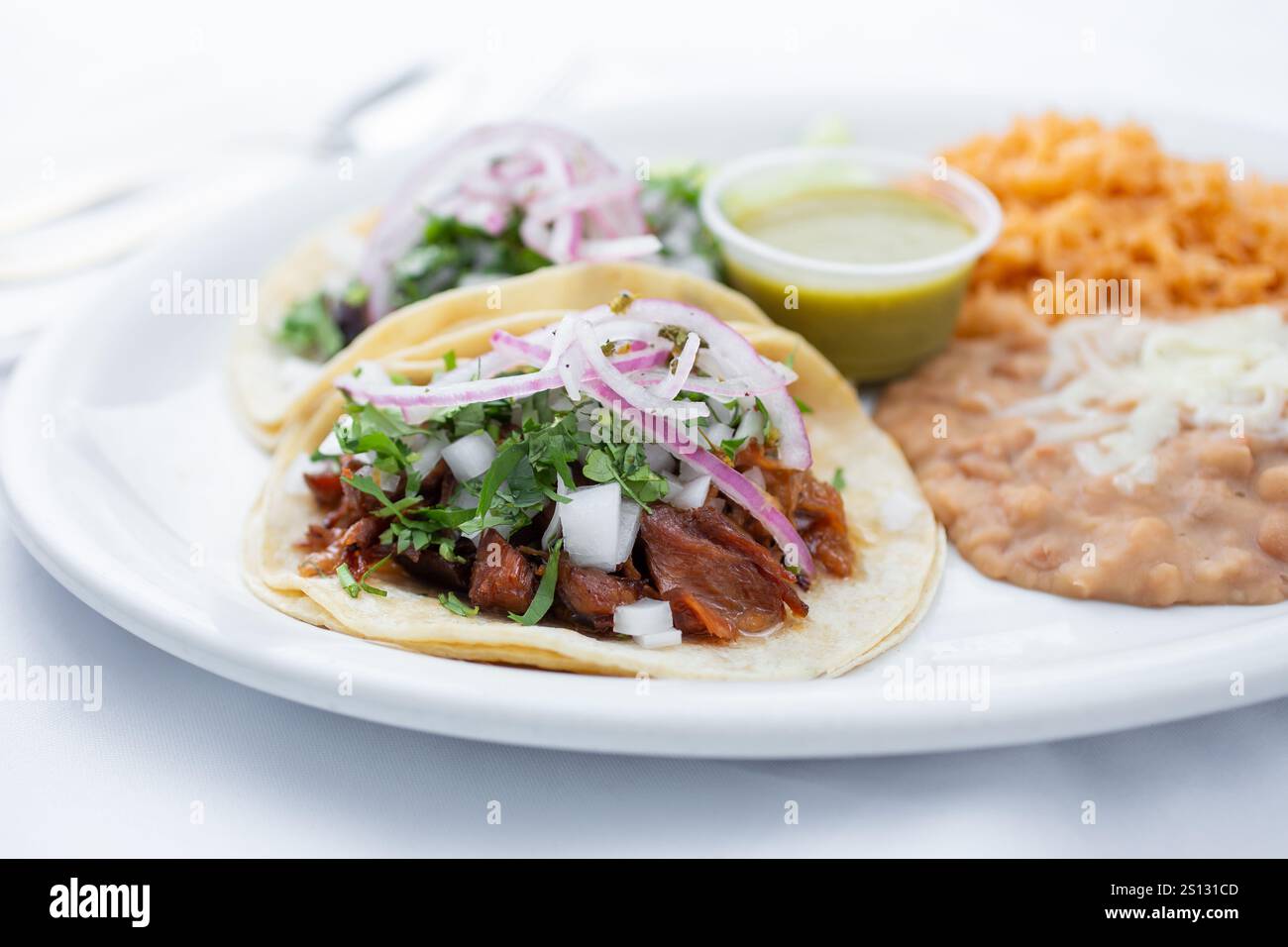 A view of two tacos al pastor with a side of beans and rice. Stock Photo