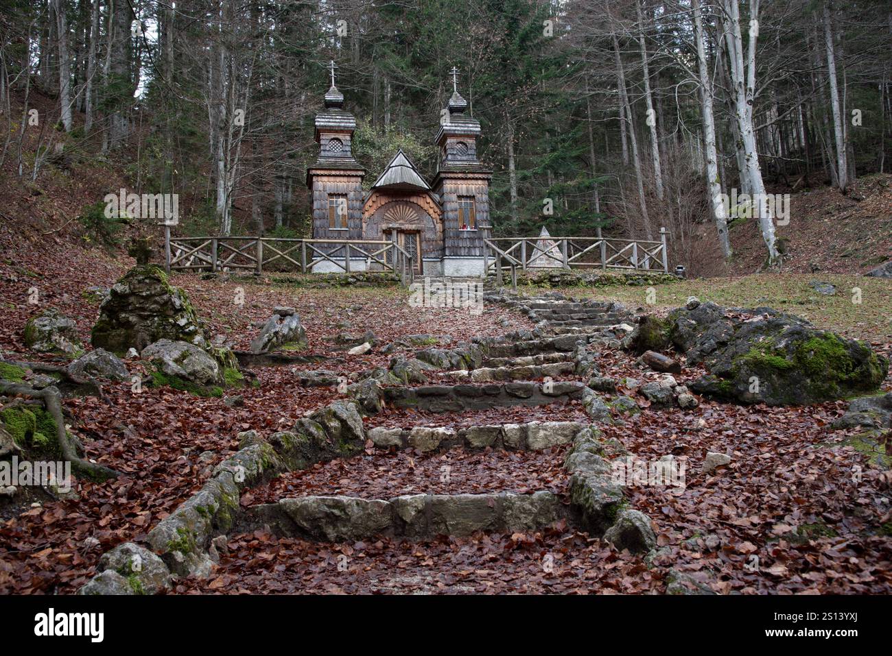 Mossy stone stairs leading up to a small wooden church nestled in an autumnal forest. Russian chapel, Kranjska Gora, Slovenia Stock Photo