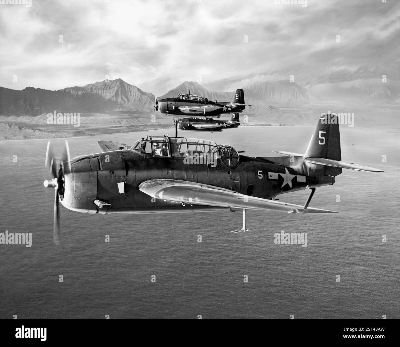 Grumman TBF-1C Avengers from USS Essex in flight off Oahu January, 1944. An American World War II-era torpedo bomber developed initially for the United States Navy and Marine Corps, but eventually used by several air and naval aviation services around the world. It entered U.S. service in 1942, and first saw action during the Battle of Midway. Despite the loss of five of the six Avengers on its combat debut, it survived in service to become the most widely-used torpedo bomber of World War II. Stock Photo