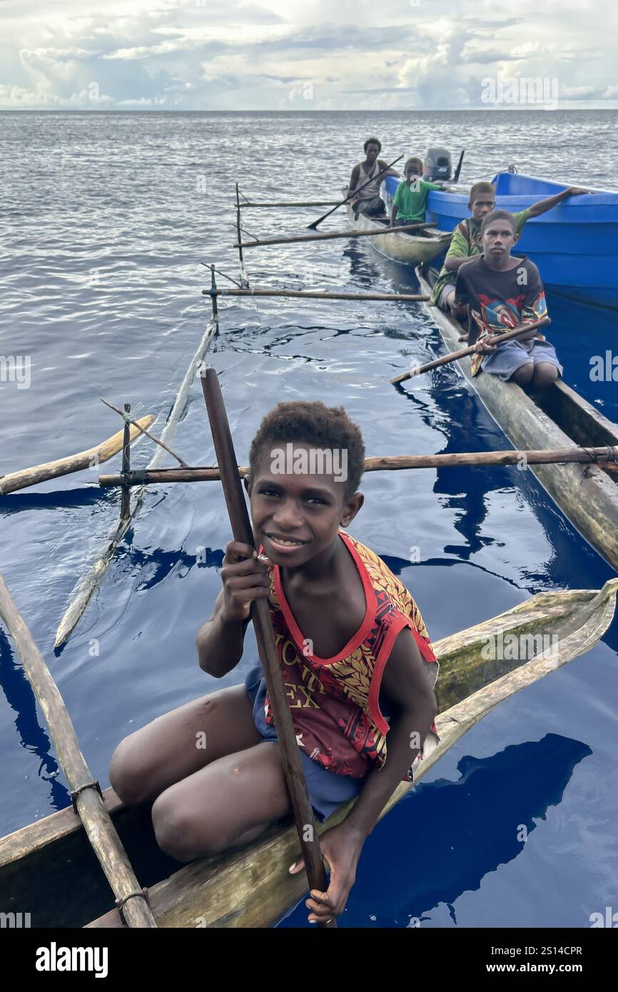 Residents of New Hanover island in their traditional dugout canoes, New Ireland province, Papua New Guinea Stock Photo