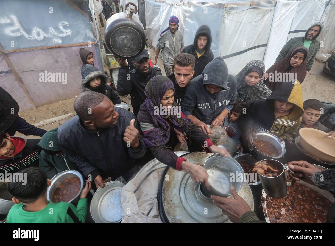 Displaced Palestinians line up to receive food from a charity soup ...