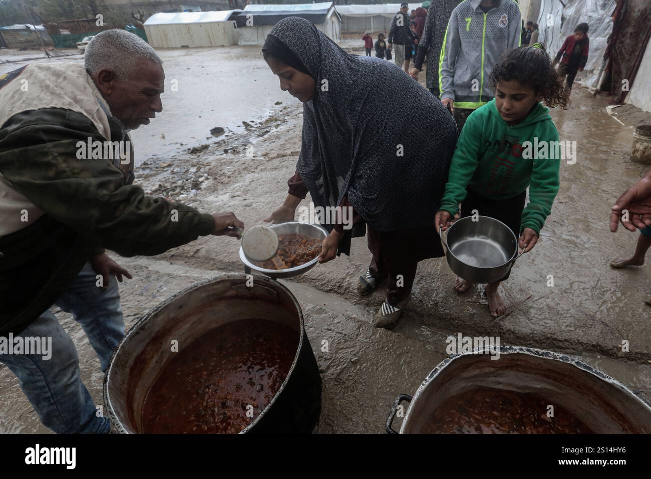Displaced Palestinians line up to receive food from a charity soup ...