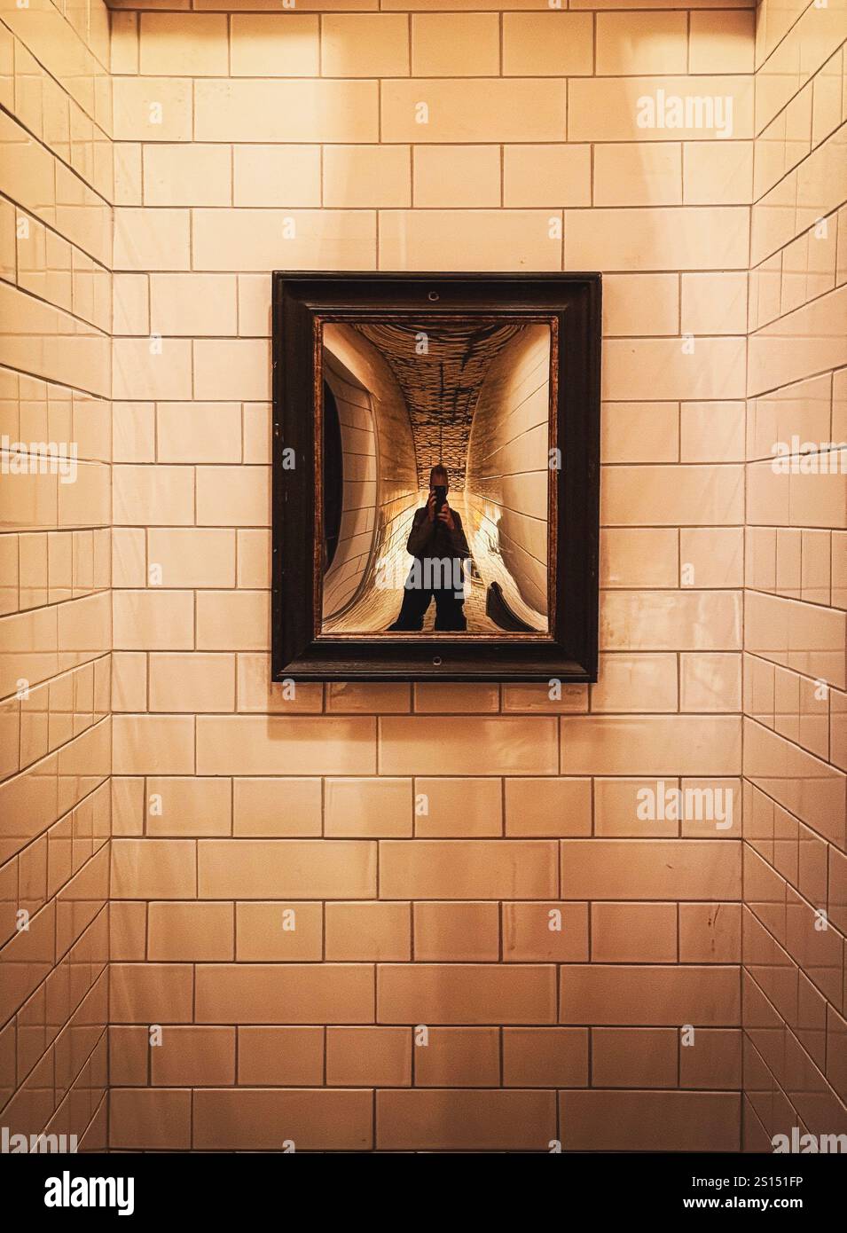 Reflection of person (photographer) in mirror in a white tiled corridor - Smartphone Captured Stock Image