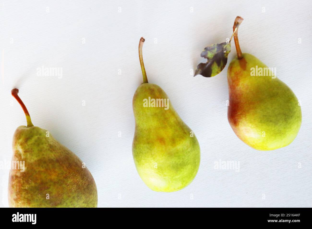 Three large freshly picked pears lie on a light background, top view. Stock Photo