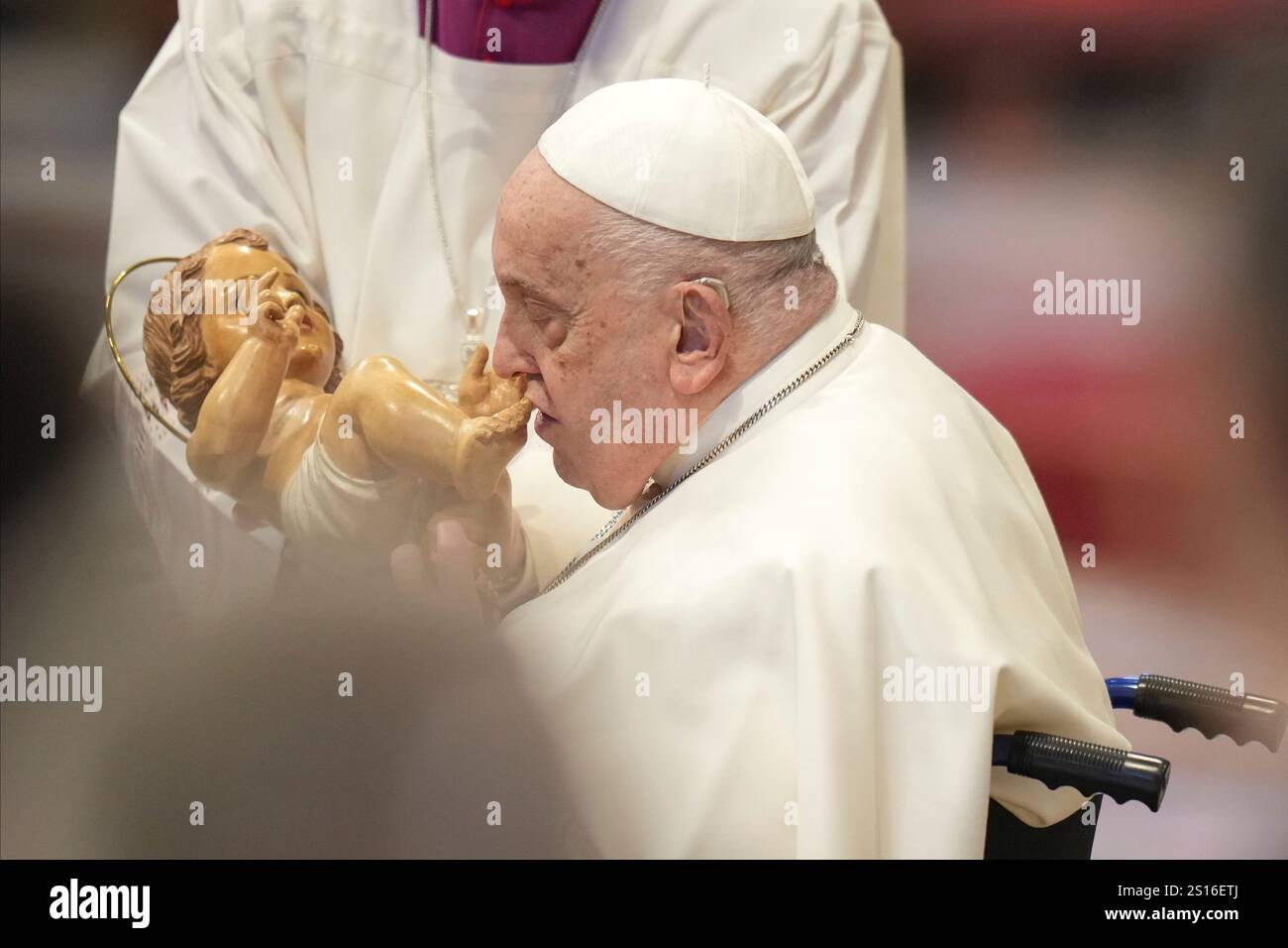 Pope Francis kisses a wooden statuette of the infant Jesus at the end