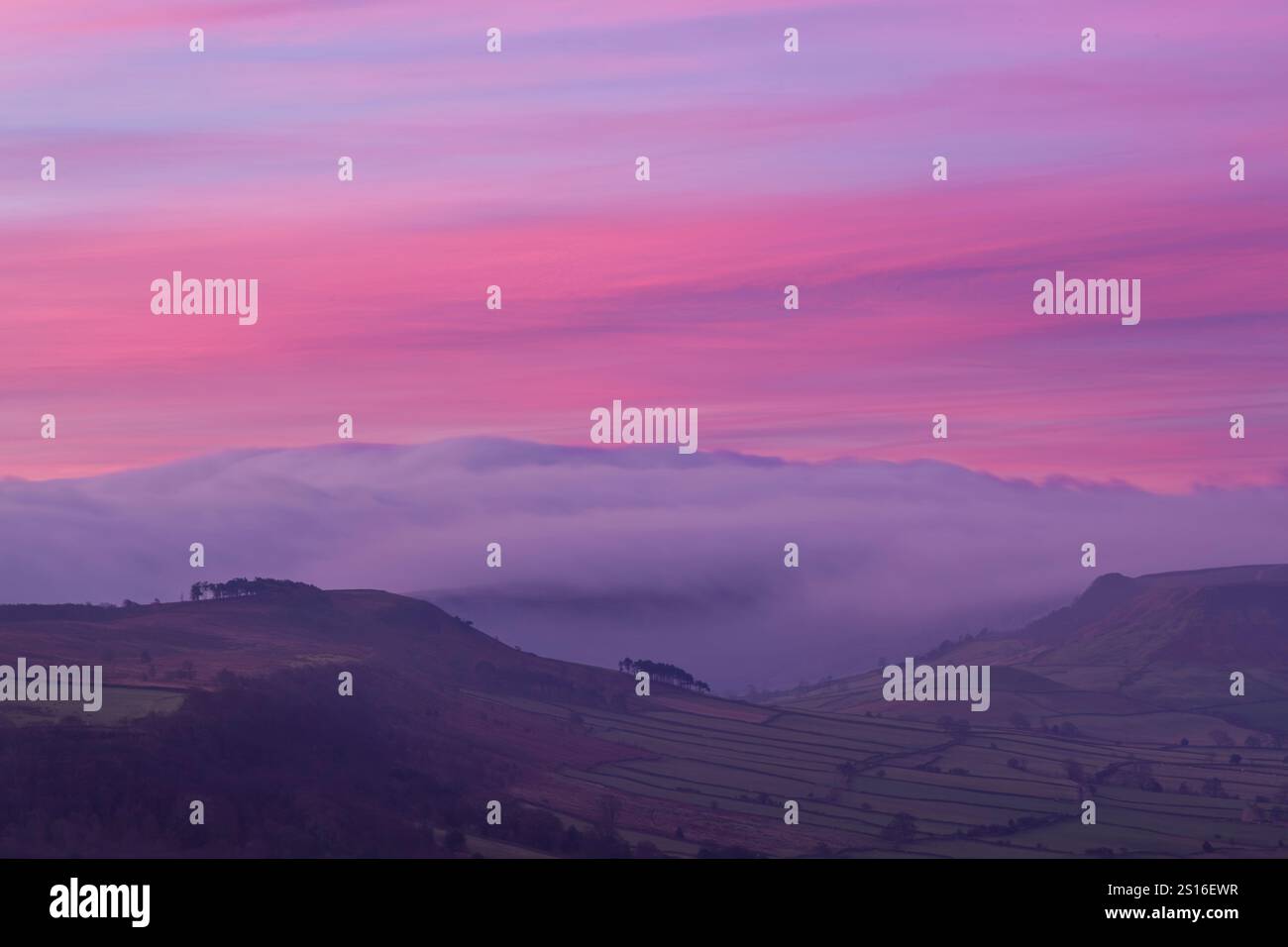 View across a fog filled Esk Valley in dawn light before sunrise beneath a colourful sky looking towards Great Fryup Dale - Stock Image