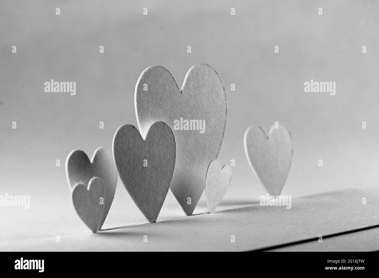 6 white paper heart cutouts on a gradient of gray Stock Photo Alamy