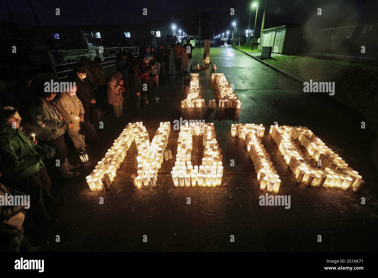 People offer a silent prayer in front of candles in Wajima, Ishikawa