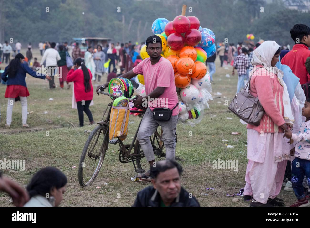 A vendor with plastic balls on a cycle looks for customers as people