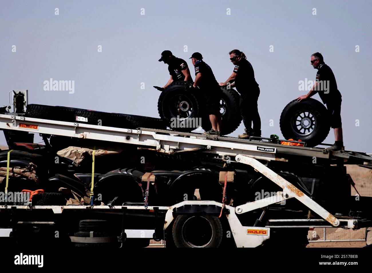 Mechanics carry wheels two days before the start of the Dakar Rally in