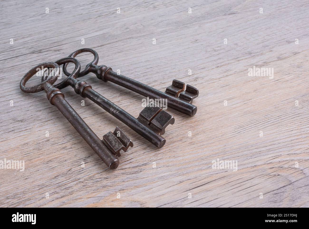 Old, rusty, iron keys on a wooden table. Stock Photo