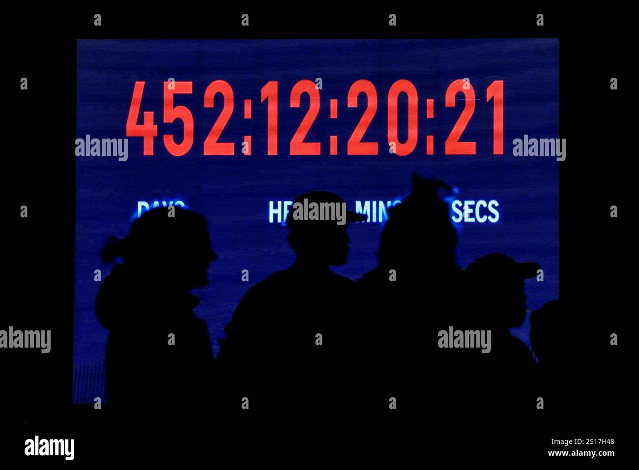 People gather in front of a clock counting the days since the Hamas