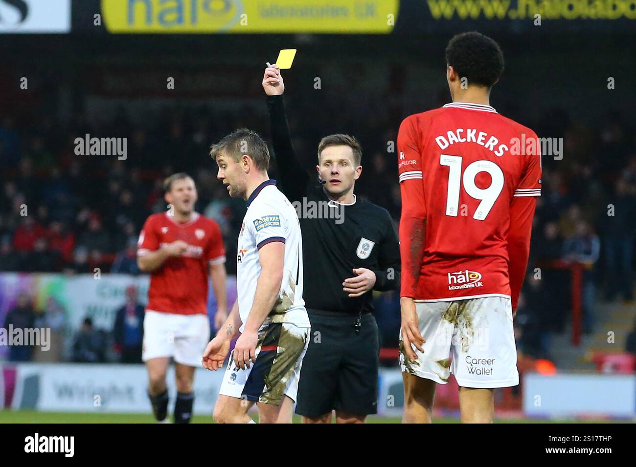 Sam Finley of Tranmere Rovers (l) is booked as he receives a yellow