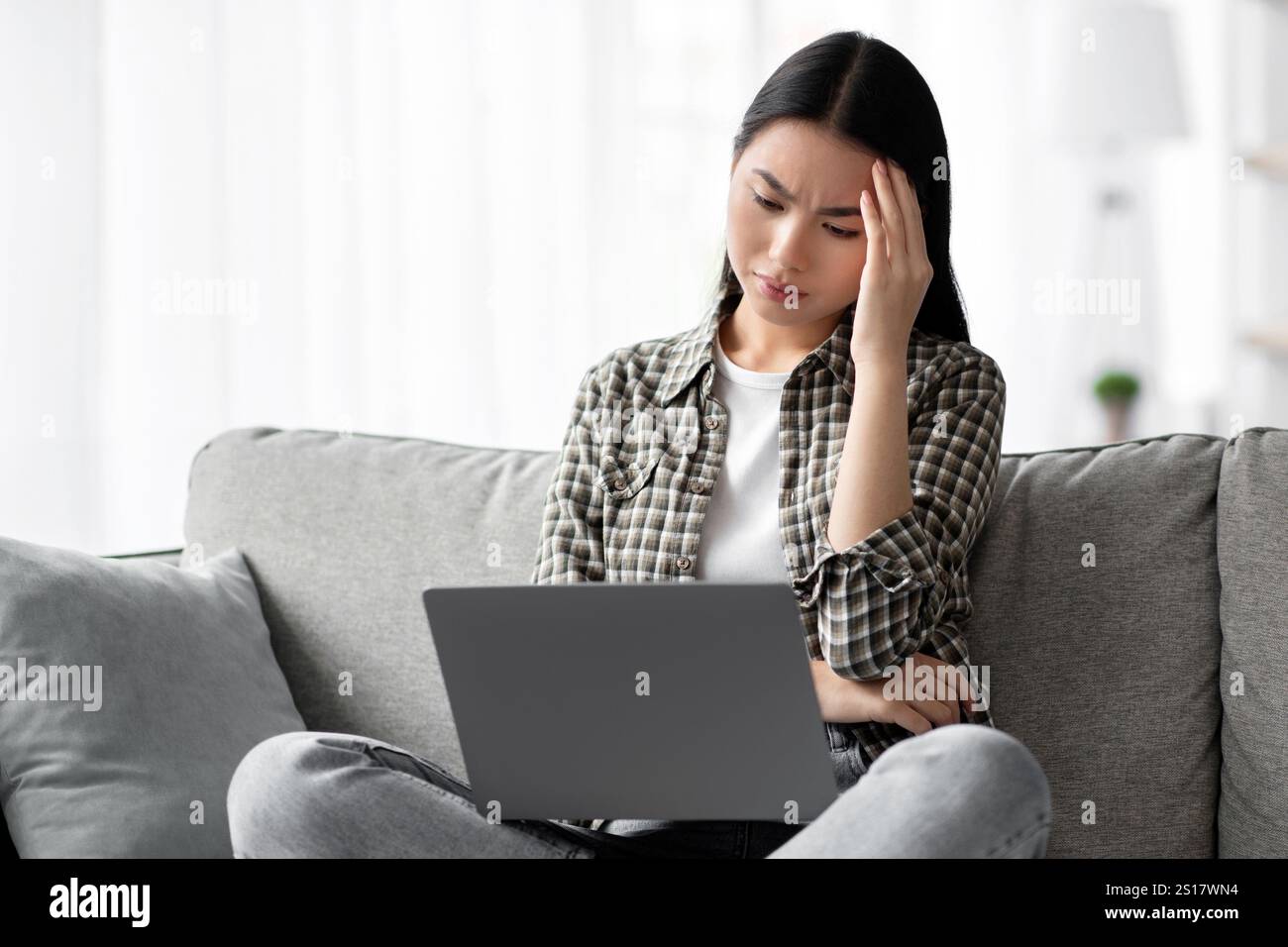 Exhausted korean lady suffering from headache while using laptop Stock Photo