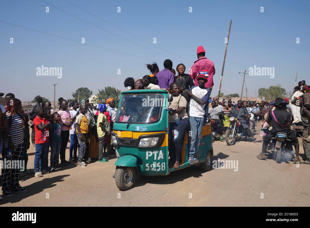 People ride on a tricycle during the Berom annual New Year celebration