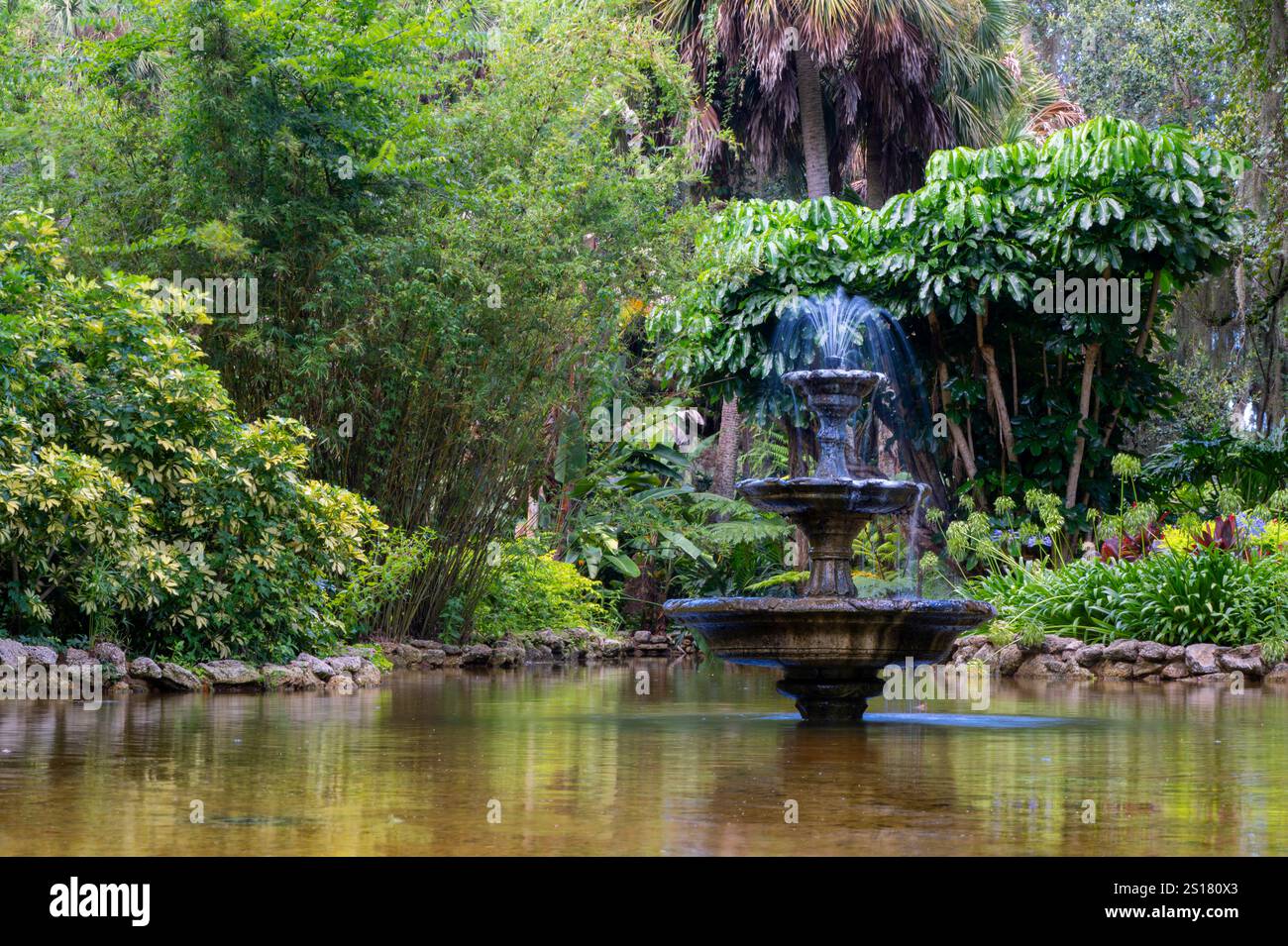 Serene Garden Fountain Surrounded by Lush Greenery in Tranquil Natural Setting Stock Photo