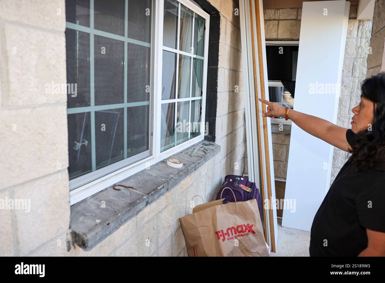 Evelyn Paguirigan points to broken windows at her home across the
