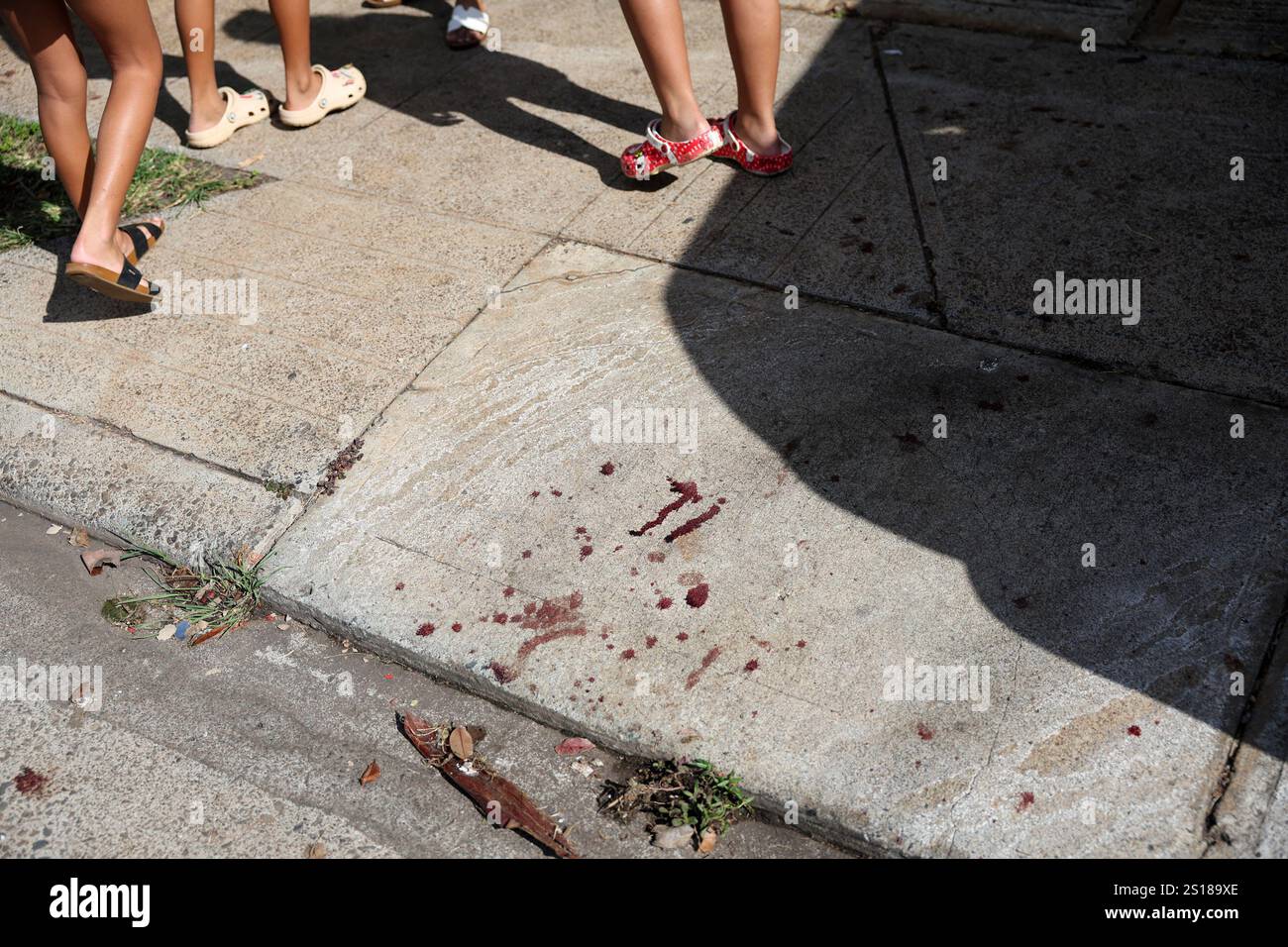 People walk past what appears to be blood on the sidewalk near the home