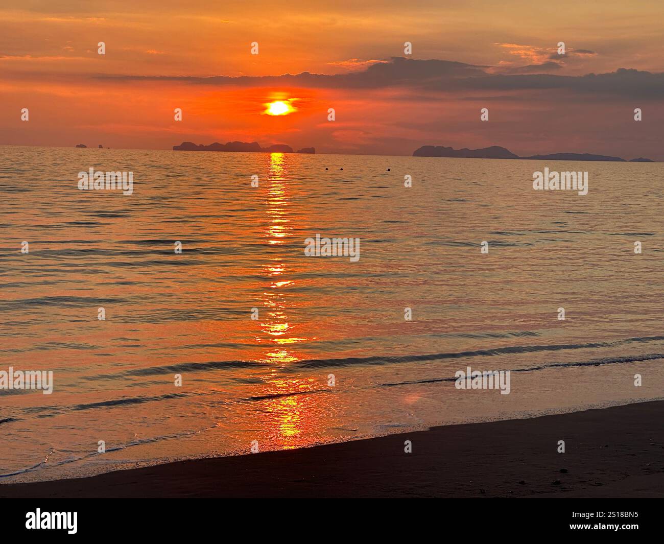 The sun sets beautifully over the ocean, reflecting on the water Stock Photo