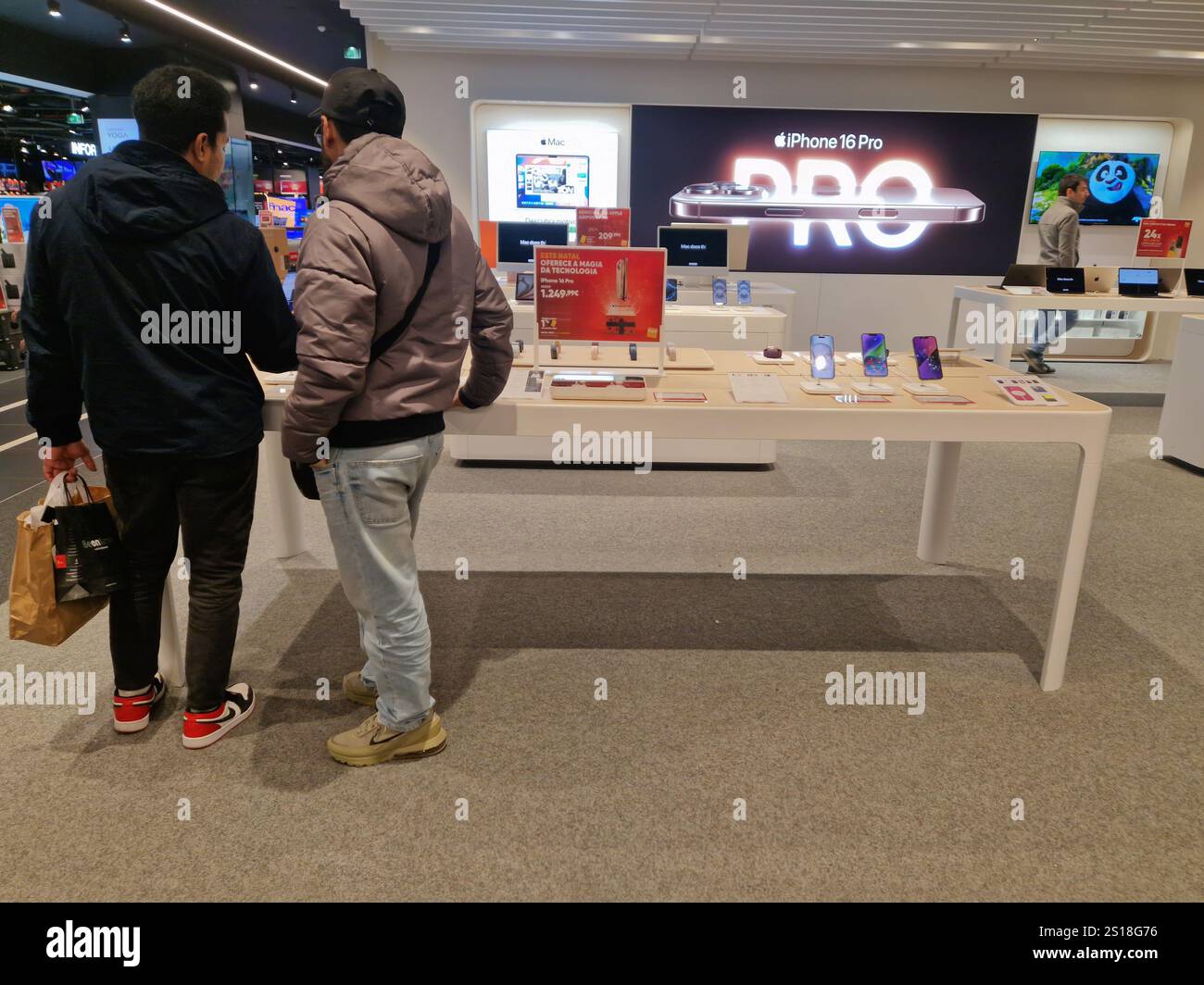 People looking at cell phones and buying in a store. iPhone mobile phones on display - Smartphone Captured Stock Image