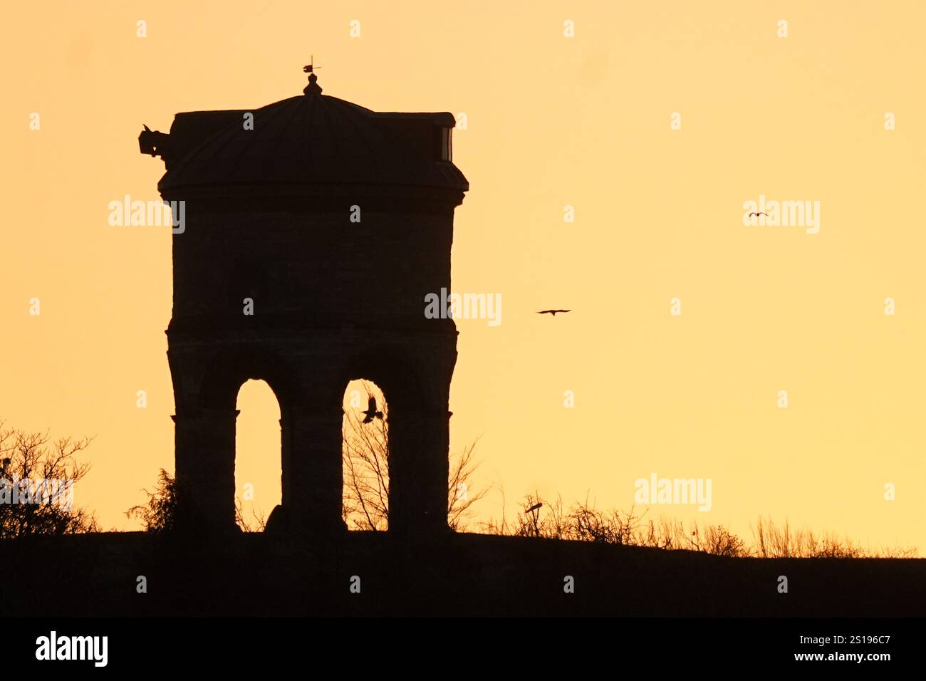 Birds fly close to Chesterton Windmill before sunrise in Warwickshire. A three-day yellow warning for snow has been issued for almost all of England and Wales and parts of Scotland this weekend as the Met Office warned that rural communities could become cut off. Picture date: Thursday January 2, 2025. Stock Photo