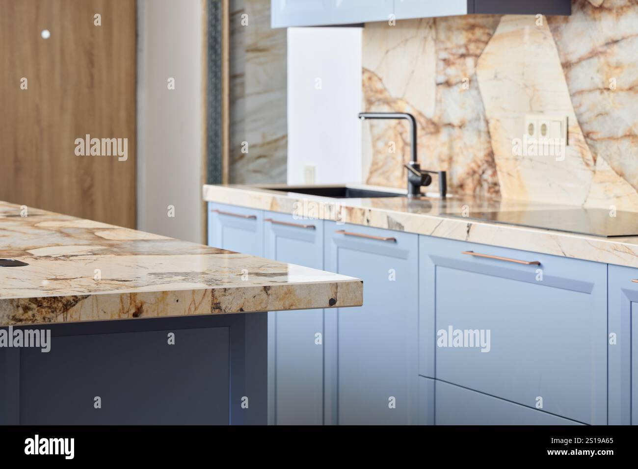 Image showcasing A modern kitchen with blue cabinets and marble countertops, blending ...