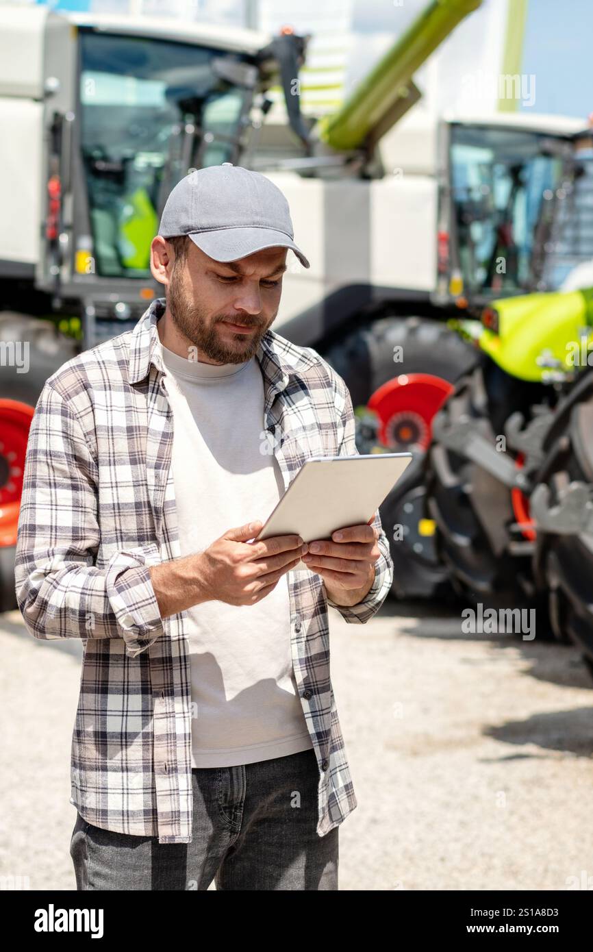 Vertical photo of male worker using digital tablet at agricultural ...