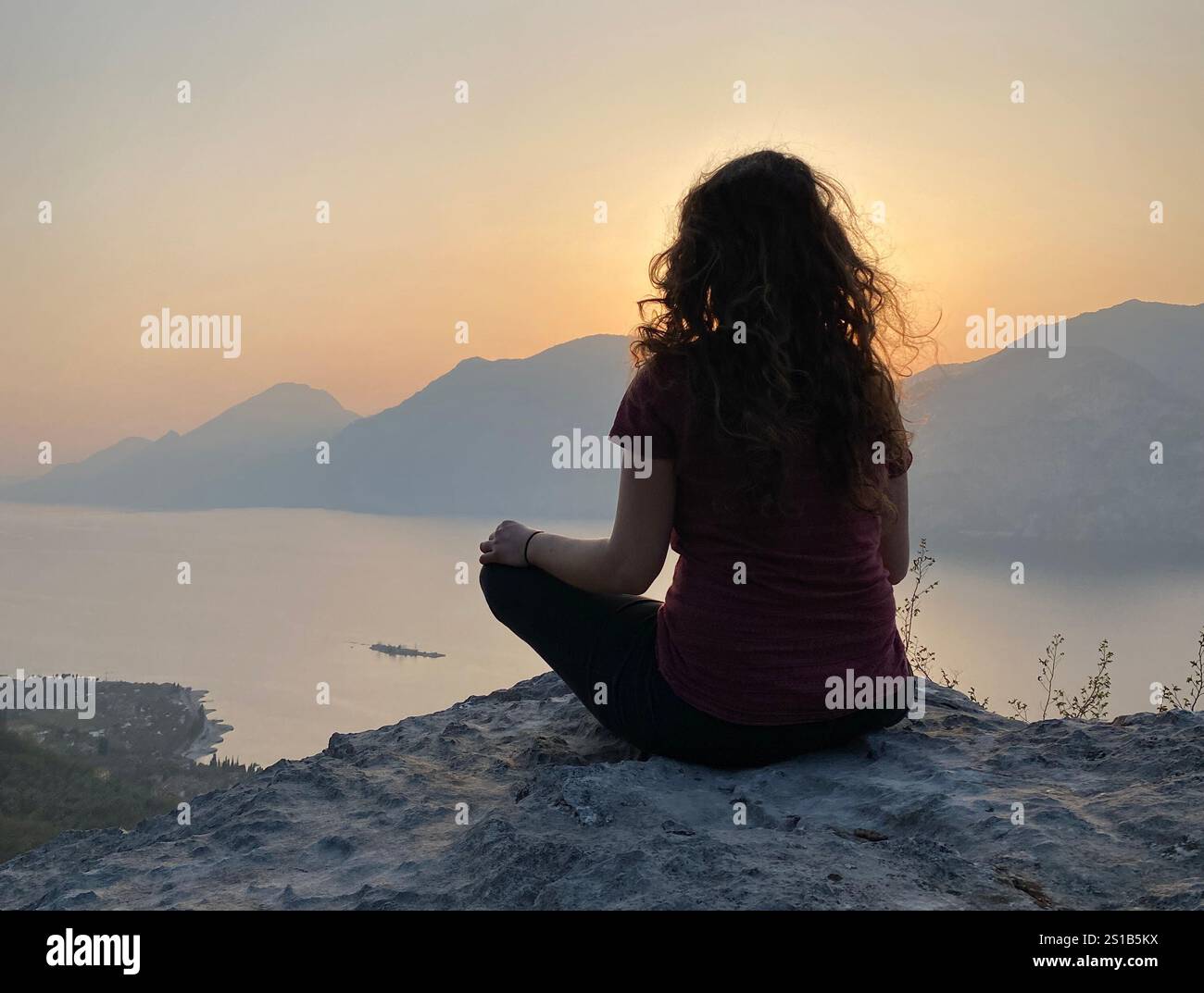 A woman meditating near lake Garda in Italy - Smartphone Captured Stock Image
