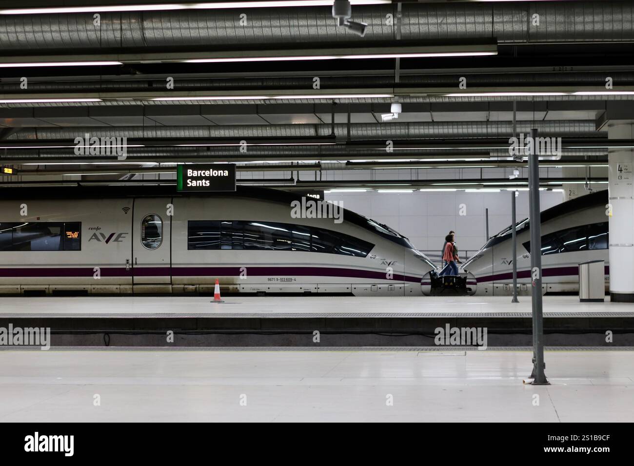 Barcelona, Spain - December 21 2024: High-speed trains at Barcelona Sants station, featuring sleek AVE trains and a lone traveler on the platform Stock Photo