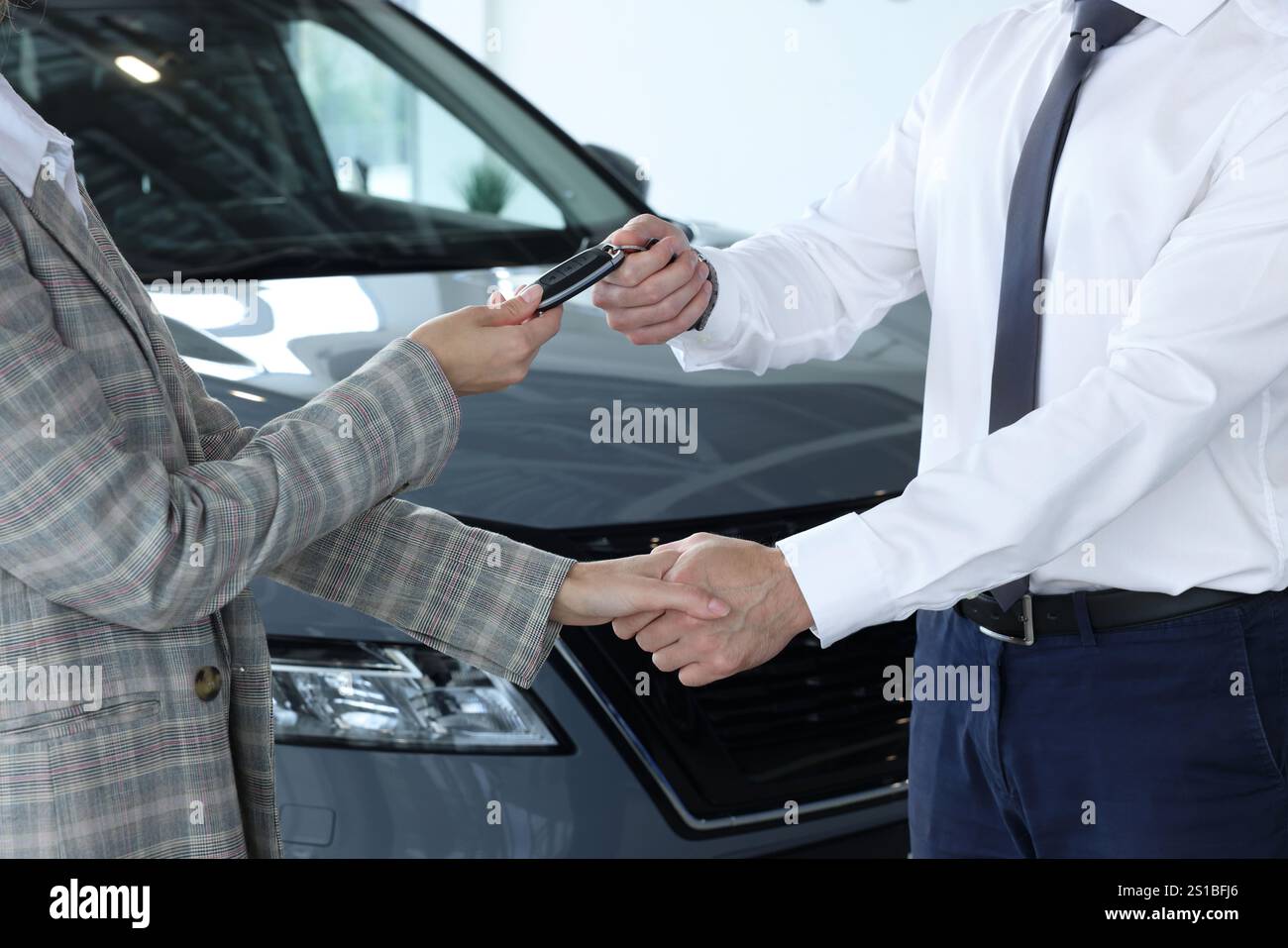 Salesman giving key to client near new car in salon, closeup Stock ...