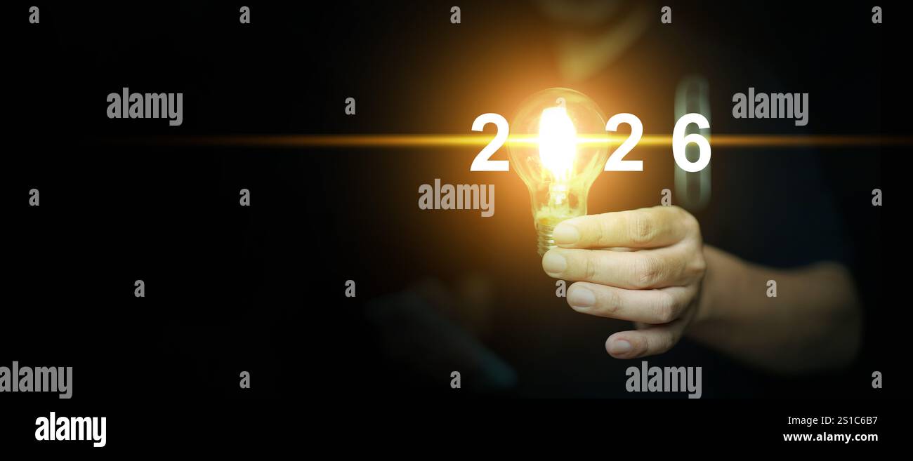 Happy new year 2026. A man holds an illuminated light bulb with the ...