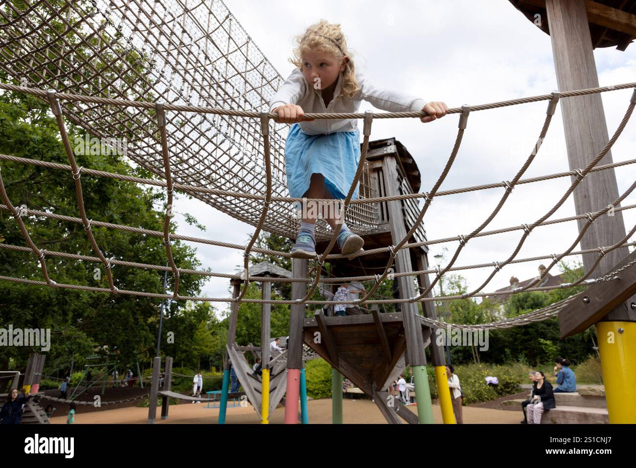 A 7 year old white girl climbs a feature in a playground at Brent Cross Town (a new development), London Stock Photo