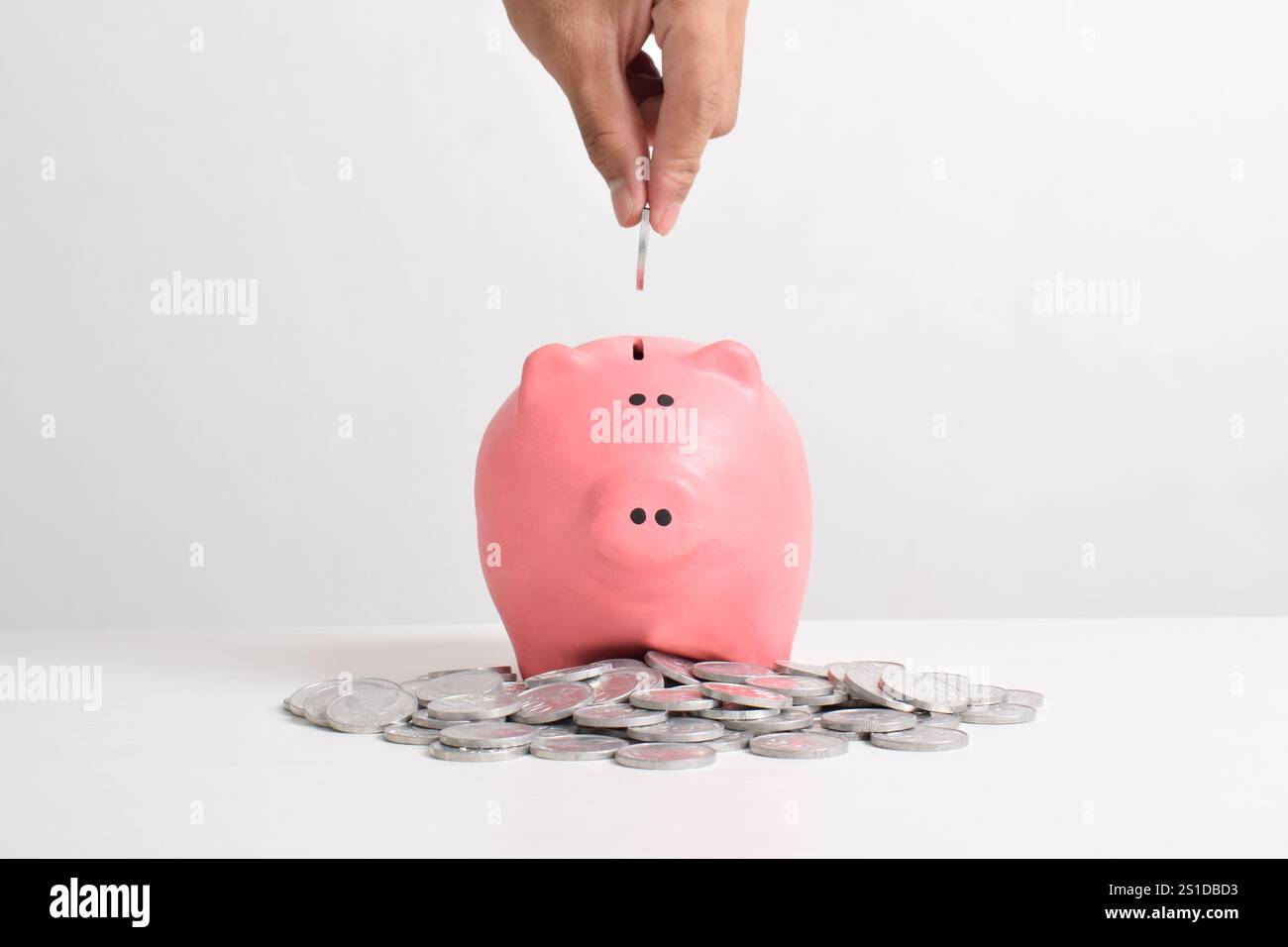 Hand putting coins into piggy bank isolated on white background with ...