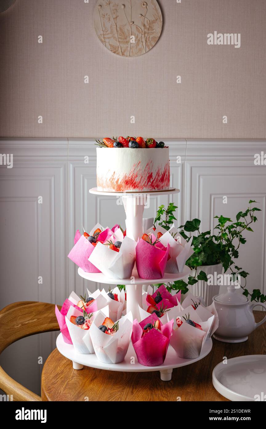 wedding cake on a stand with cupcakes Stock Photo