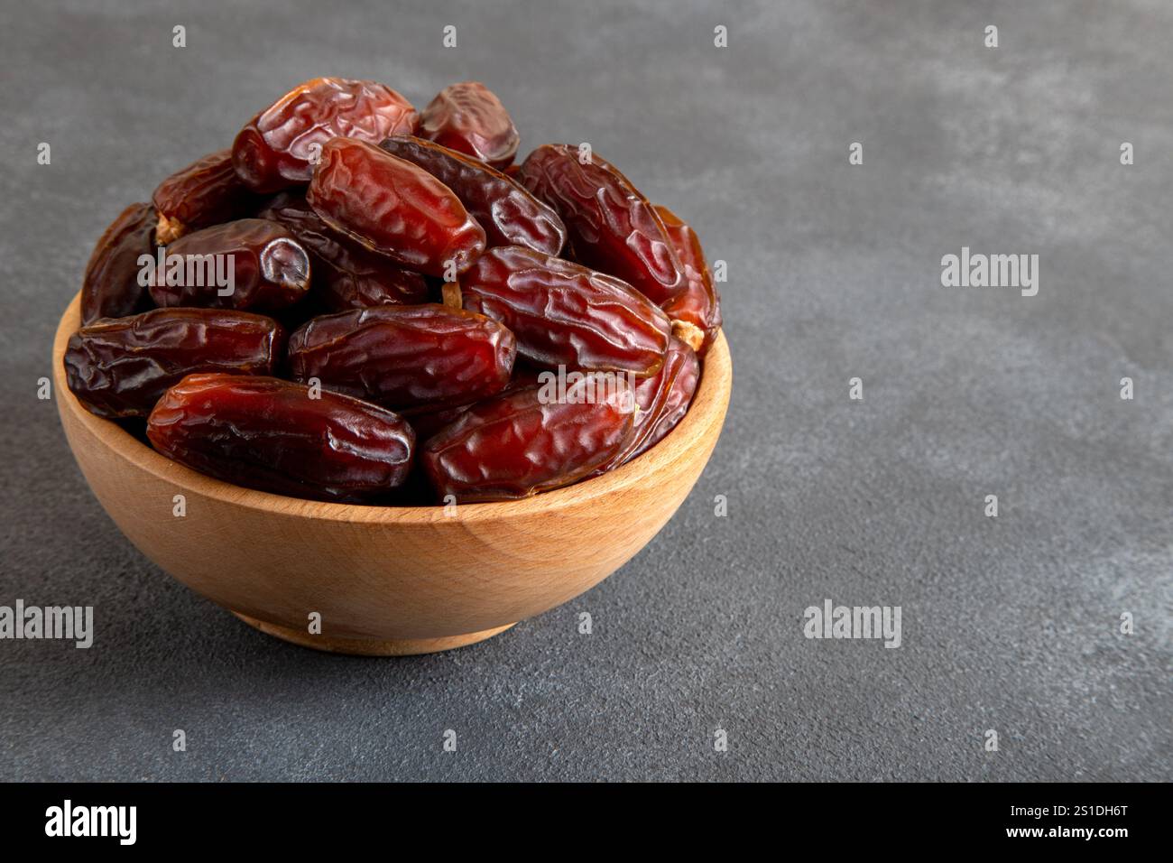 Large dates fruit in a wooden bowl, top view Stock Photo