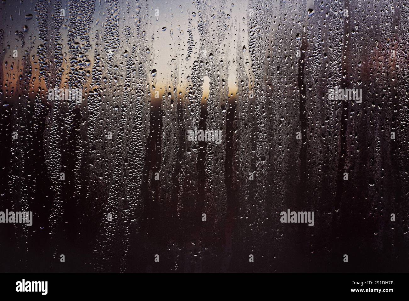 Raindrops on a window with sunset sky Stock Photo