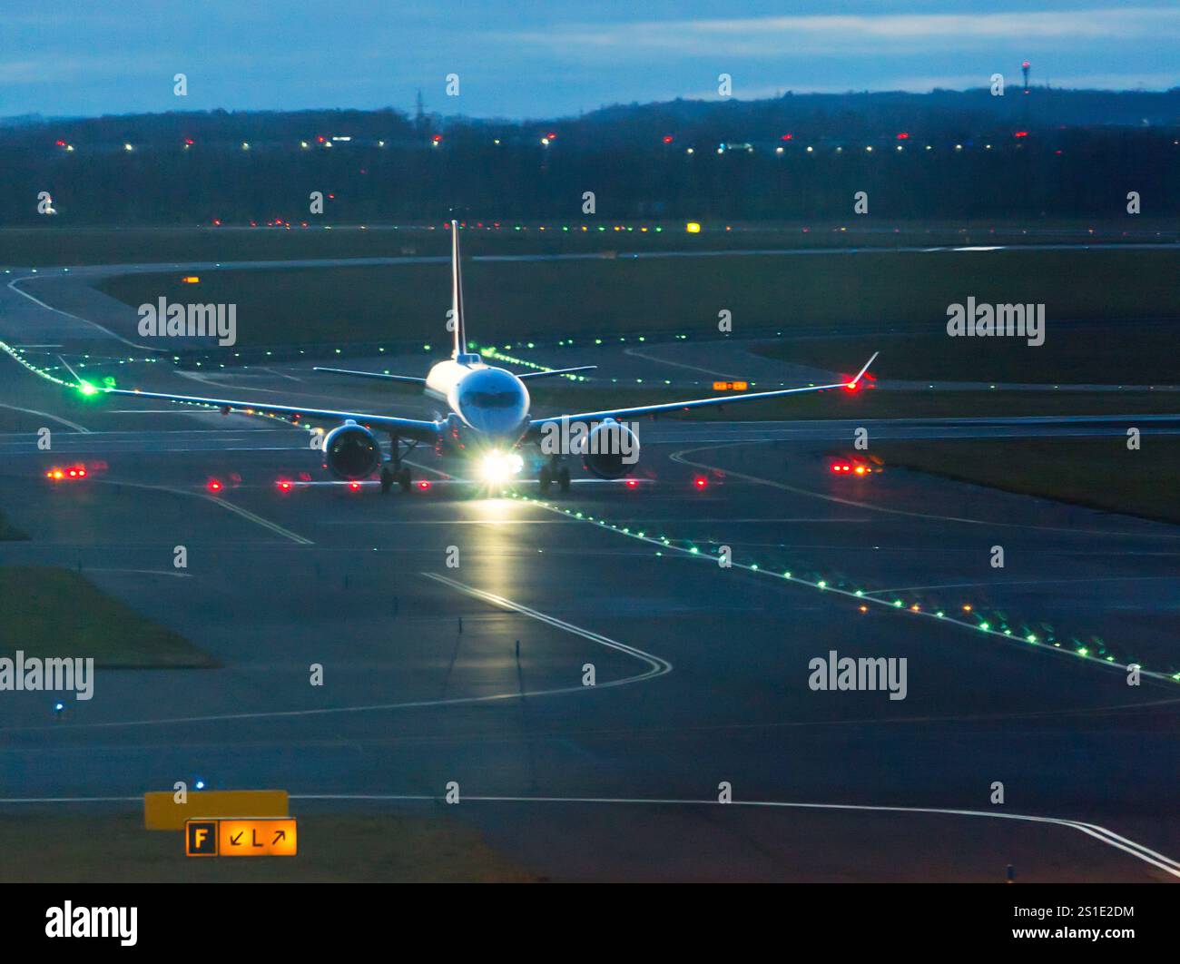 Commercial jet aircraft on runway with lights, approaching terminal ...