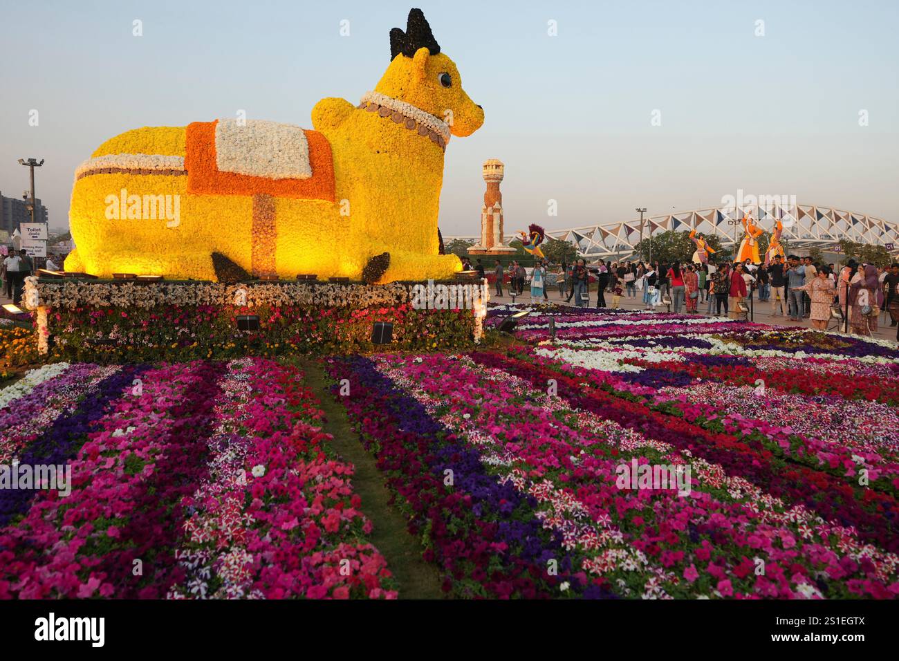 Visitors look at a sculpture of Nandi made by flowers at a Flower Show