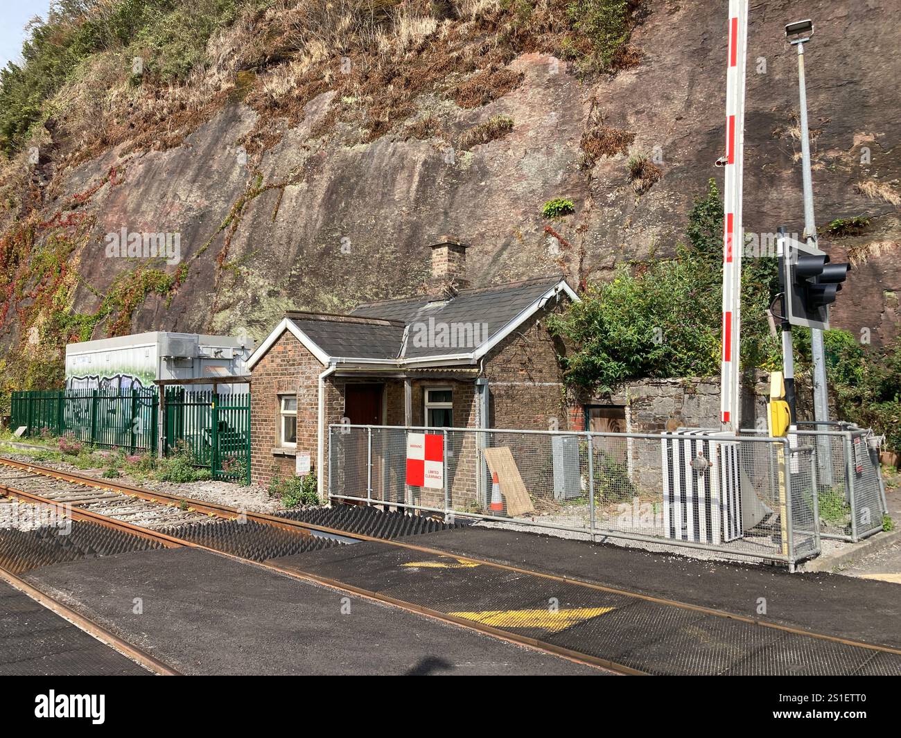 Railway level crossing with barriers and small building on the railway line in Ireland, close to Cork Kent railway station - Smartphone Captured Stock Image