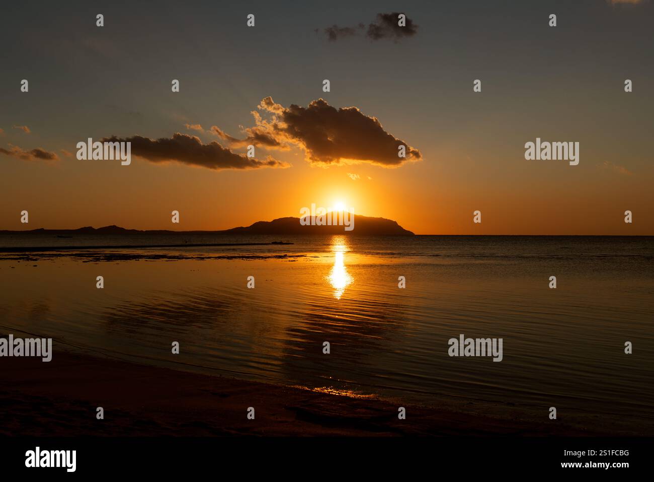 Beautiful fiery red sunrise over the top of the mountainous island of ...