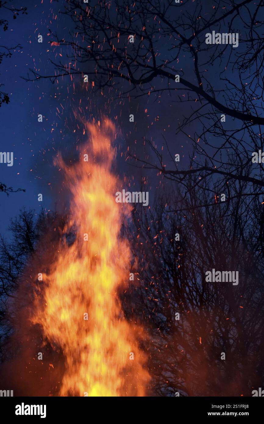 Crackling flames and red-hot flying sparks against a black-blue night sky. Portrait format. Crackling flames and red-hot sparks against a black-blue n Stock Photo