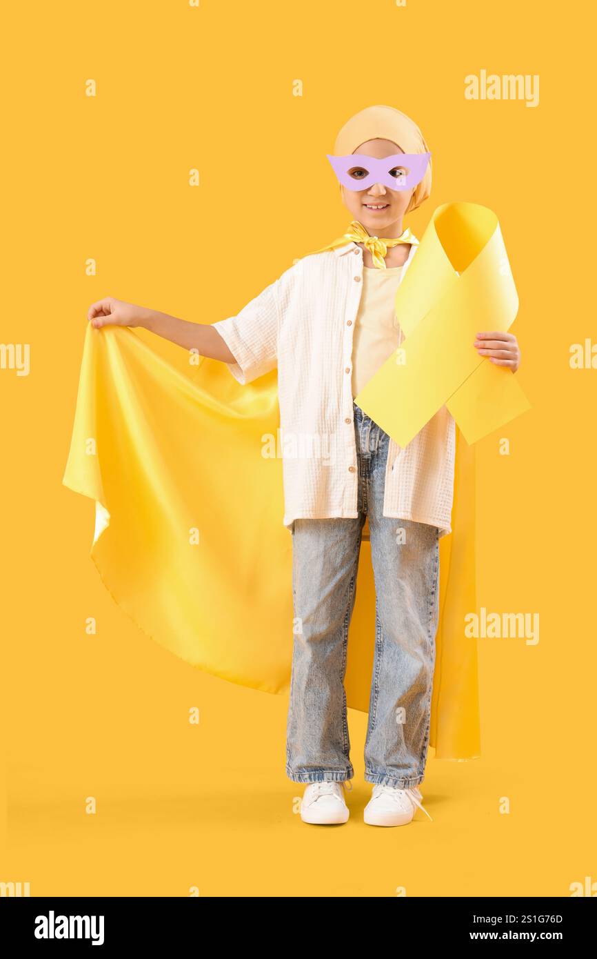 Little girl dressed as superhero after chemotherapy with yellow ribbon
