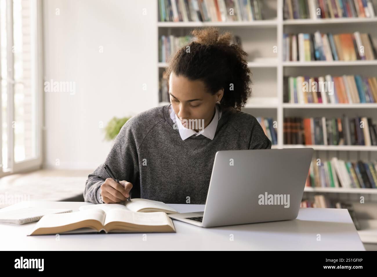 Focused male student work on project at library using notebook Stock Photo