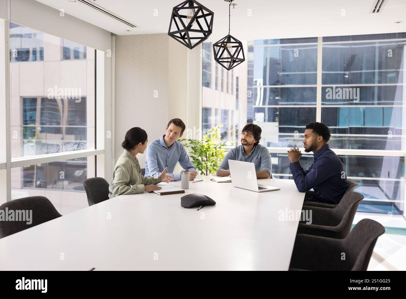 Diverse group of professional colleagues talking at large white table ...