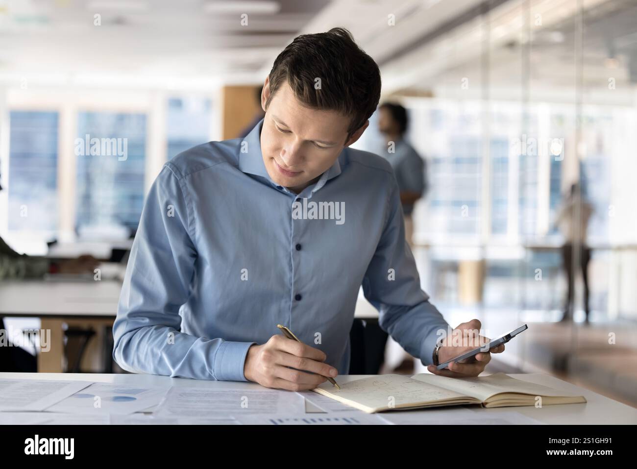 Focused young Caucasian company manager man analyzing project documents Stock Photo