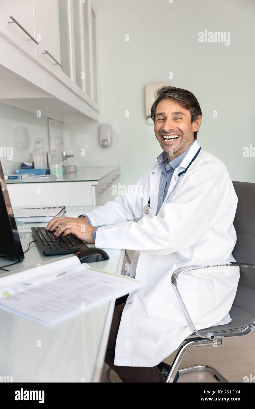 Happy successful Hispanic practitioner man working at desktop Stock Photo