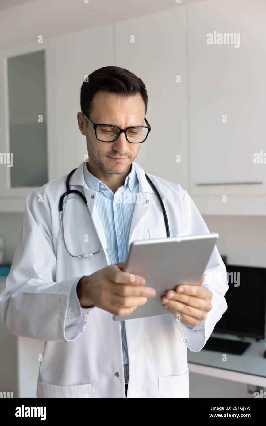 Serious young doctor man using digital tablet for work Stock Photo