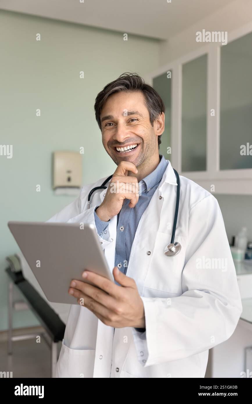 Cheerful Hispanic male general practitioner man using tablet Stock Photo
