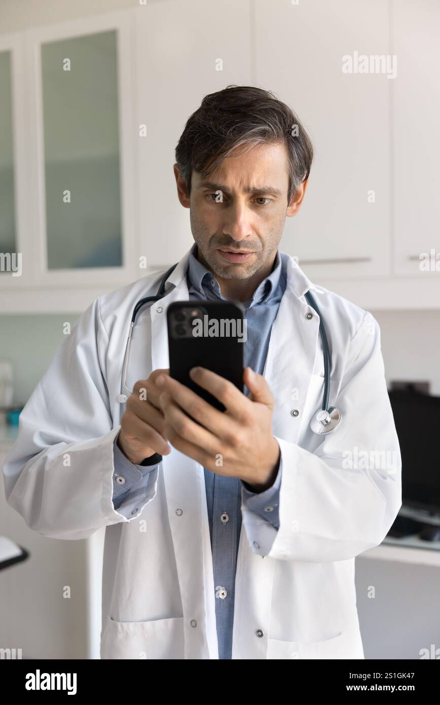Serious doctor man using mobile phone for Internet communication Stock Photo
